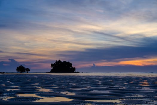 Beautiful colorful sunset near the small exotic island with palms