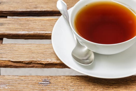 White cup of black tea on wooden battens.