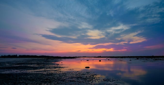 Colourful sunrise and stones in  low tide ocean water