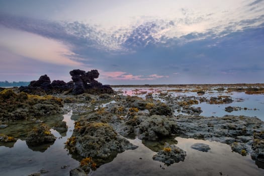 Colourful sunrise and stones in  low tide ocean water