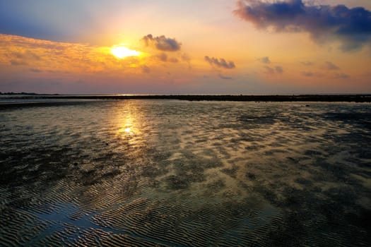 Colourful sunrise and the sand during low tide ocean water