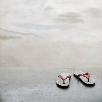 COLOR PHOTO OF PAIR OF FLIP FLOPS ON CONCRETE GROUND