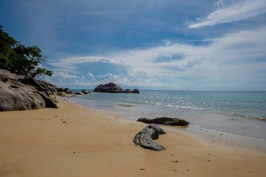 Tropical island sea shore with sand palms and rocks. Beautiful sunny day