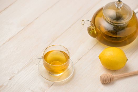 Cup of lemon tea with honey on white wooden background.