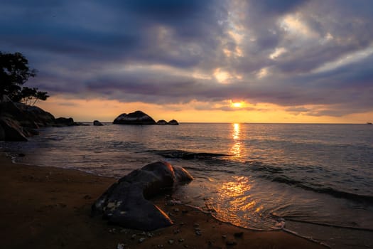 Great sunset at beautiful tropical island. Sand, trees, rocks, stone, sea waves and clouds