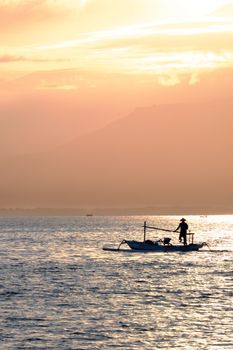 Indonesian fisherman in the boat after the sunrise with Lombok island in the background