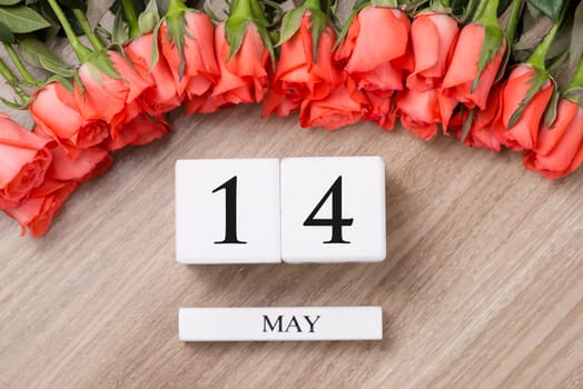 Cube shape calendar for MAY 14 on wooden table with roses