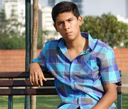 Teen Hispanic Male Sitting On Park Bench