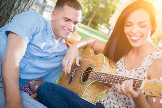 Happy Mixed Race Couple at the Park Playing Guitar and Singing Songs.