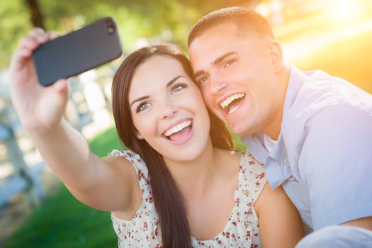 Happy Mixed Race Couple Taking Self Portrait with A Smart Phone in the Park.