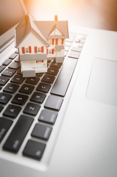 Miniature House And Laptop Computer Resting on Desktop.