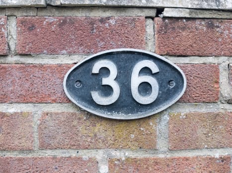 a number plate on a brick wall with 36 on it oval black sign stamp metal tag plate sign