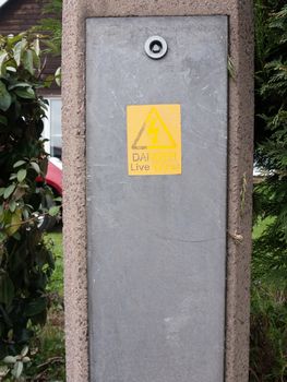 a danger live wires yellow and black emergency warning sign on a metal plate and concrete box outside warning careful