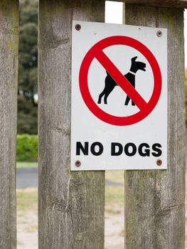 a sign saying no dogs red black and white park safety clean area private icon circle crossed on fence near playground