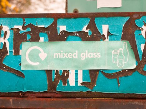 a green recycling sign near glass recycle plant and bins saying mixed glass with pictures of jars and bottles environment clean