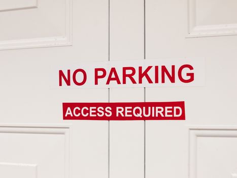 a white and red no paring access required sticker sign attached to outside garage door restriction english uk law private house car space driving