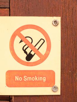 a nailed and screwed down sign red and black and white saying no smoking with a circle crossed of a cig cigarette no allowed safety health private restrictions law safety