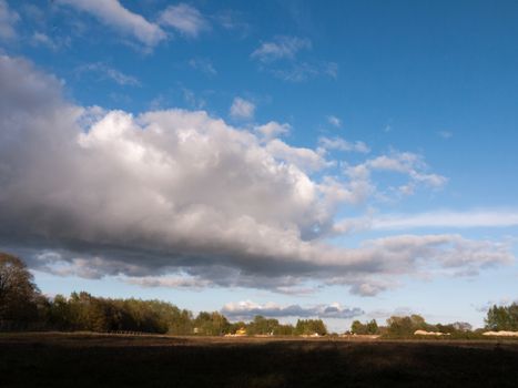 a big rolling cloud of white over a landscape shot of farmland with open space in the country with no animals and no people at rest relaxing and stormy in spring