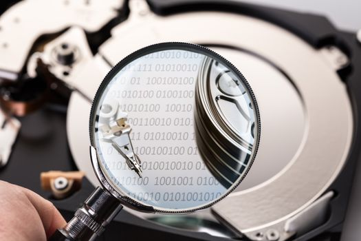 Disassembled computer hard disk and magnifier close-up
