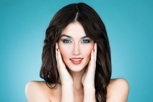 Beautiful woman with long brown hair. Closeup beauty portrait of a fashion model posing at studio on blue background