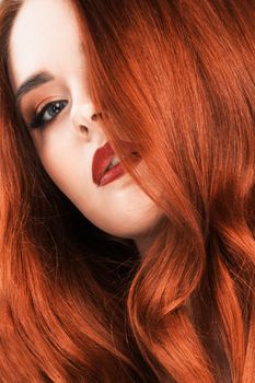 Gorgeous redhead girl with wavy hair closeup beauty studio portrait