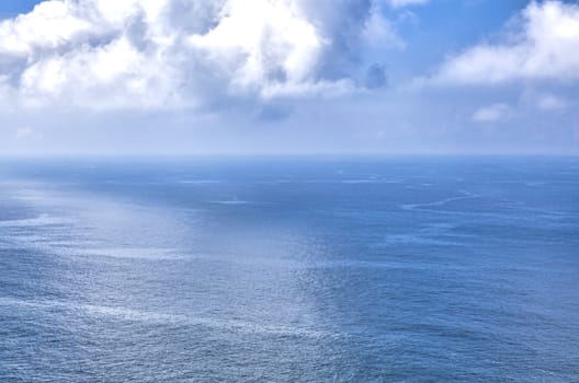 Cloudy blue sky above a blue surface of the sea