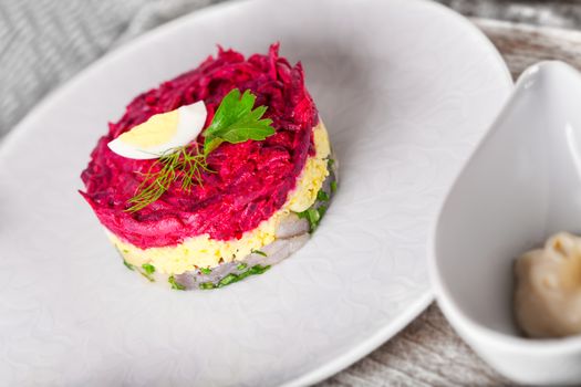 Salad with beet and herring on a white plate