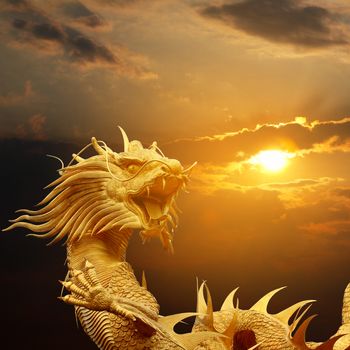 Golden chinese dragon on dramatic sky at sunset.