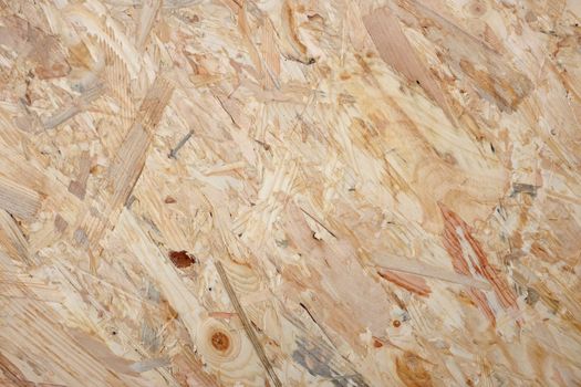 Coarse wooden flakeboard abstract background. Pale OSB sheet with dark wood knots and patterns.