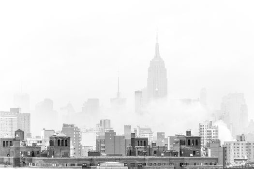 New York City, United States of America - March 24: Misty Manhattan Dimond Reef skyline with Empire State Building and skyscrapers seen from Brooklyn Bridge on March 24, 2015 in black and white.