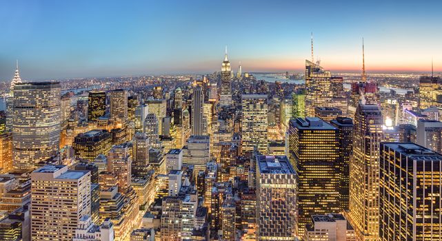 New York City. Manhattan downtown skyline with illuminated Empire State Building and skyscrapers at dusk.