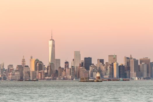 New York City Manhattan downtown skyline at dusk with skyscrapers illuminated over Hudson River panorama. Horizontal composition, copy space.