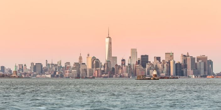 New York City Manhattan downtown skyline at dusk with skyscrapers illuminated over Hudson River panorama. Horizontal composition.