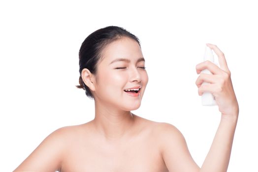 Beautiful asian woman applying spray water on face isolated white background.