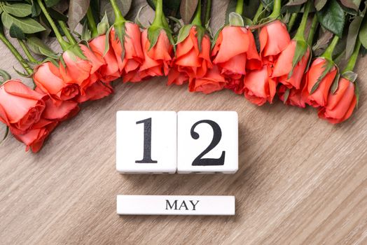 Cube shape calendar for MAY 12 on wooden table with roses