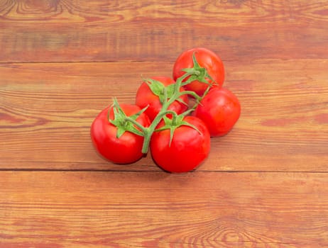 Branch of the ripe red tomatoes with droplets of dew on a surface of the old wooden planks 
