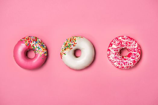 Donuts with icing on pastel pink background. Sweet donuts.