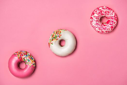 Donuts with icing on pastel pink background. Sweet donuts.