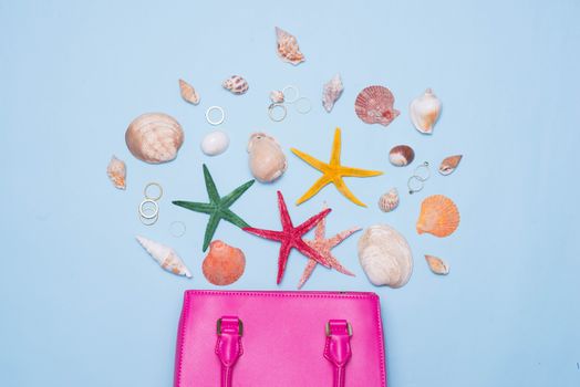 Summer concept. Pink handbag with accessories on light blue background