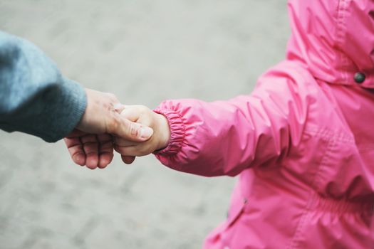 A little girl leads by the hand of her mother, a close-up of two hands. The concept of knowledge of the new.