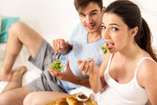 Young couple eating the breakfast on the bed