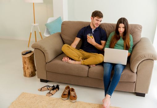 Young couple sitting on the sofa and watching something on a laptop