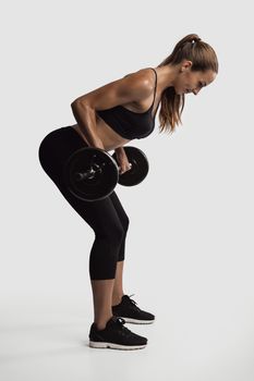 Shot of a beautiful young woman in a workout gear lifting weights