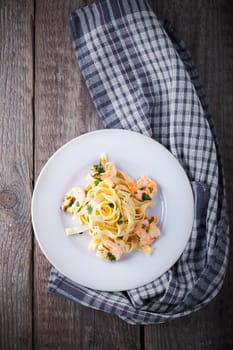 Tagliatelle with shrimps on a wooden surface