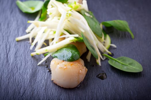 Scallop salad with apple, spinach on a stone plate 