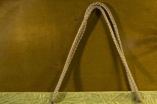 Rope handles from a paper bag on a wooden background