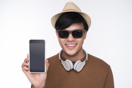 Smart casual asian man seated on chair, showing smartphone screen in studio background