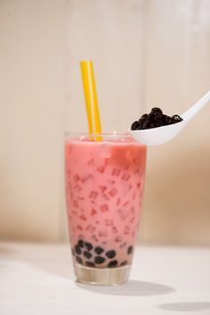 Boba / Bubble tea. Homemade Strawberry Milk Tea with Pearls on wooden table.