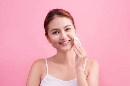Healthy fresh asian girl removing makeup from her face with cotton pad.
