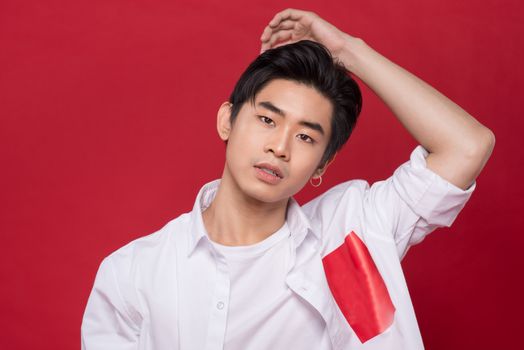 Portrait of elegant young handsome asian man over red background. Cool fashion male model.